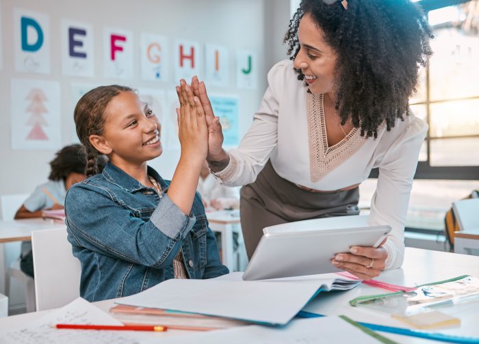 Tablet, high five and teacher with child education, learning and support, achievement and classroom goal. Mentor, black woman or person and girl in success hand sign for English, language development.