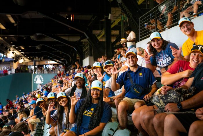 Fans in the stands at a baseball game posing for a photo.