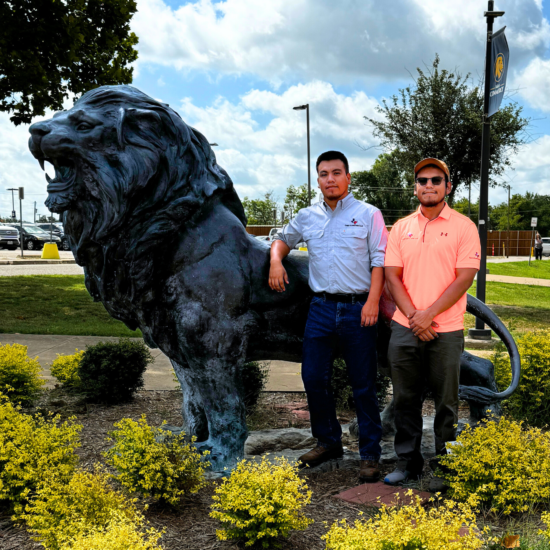 Two people standing in front of a life-sized Lion statue.