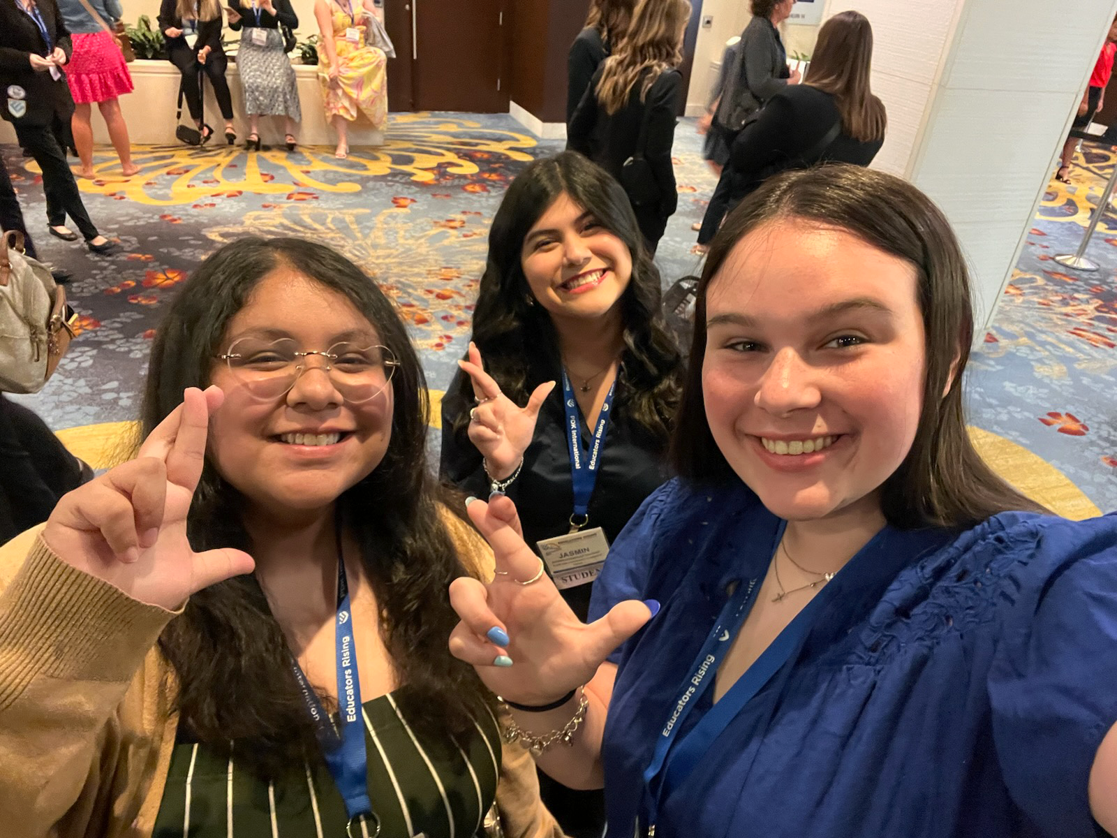 Three female students show the "Lucky Lion" hand sign at a national conference.