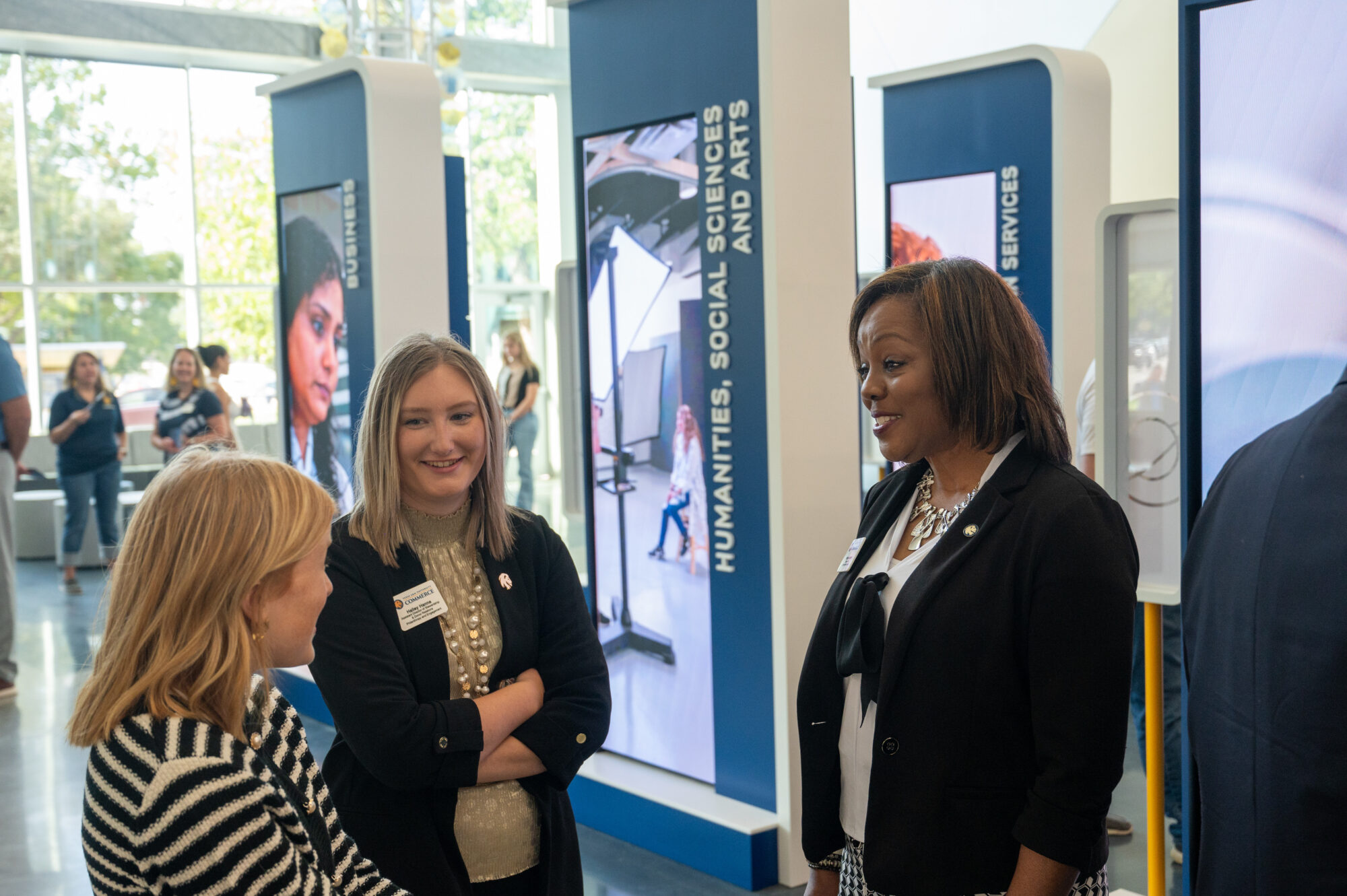 Three guests stand in a circle and talk. They are all smiling.