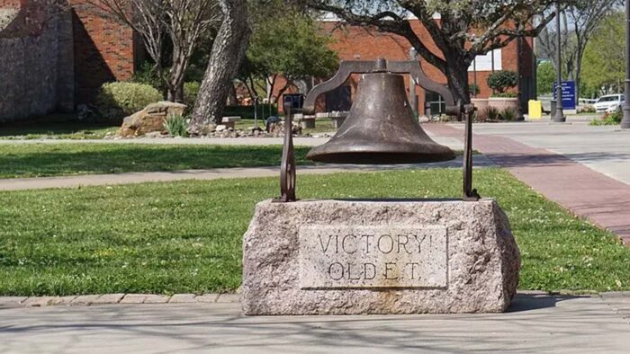 Metal bell is set on a stone base with the words "Victory Old E.T." etched in the stone.