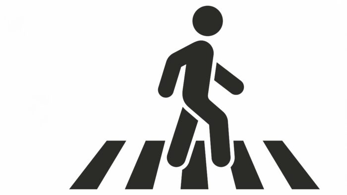 Black and white illustration shows a stick person crossing a crosswalk.