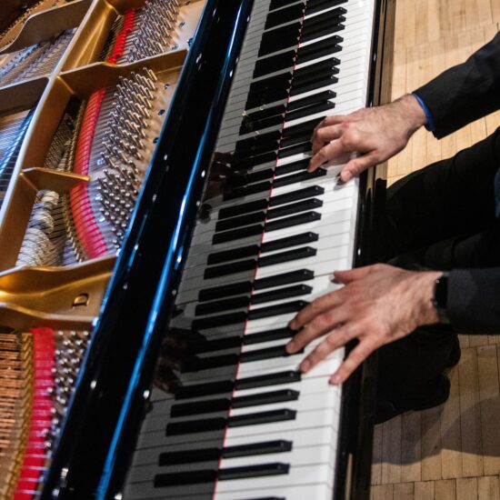 A close up photo of a pair of hands playing a piano.