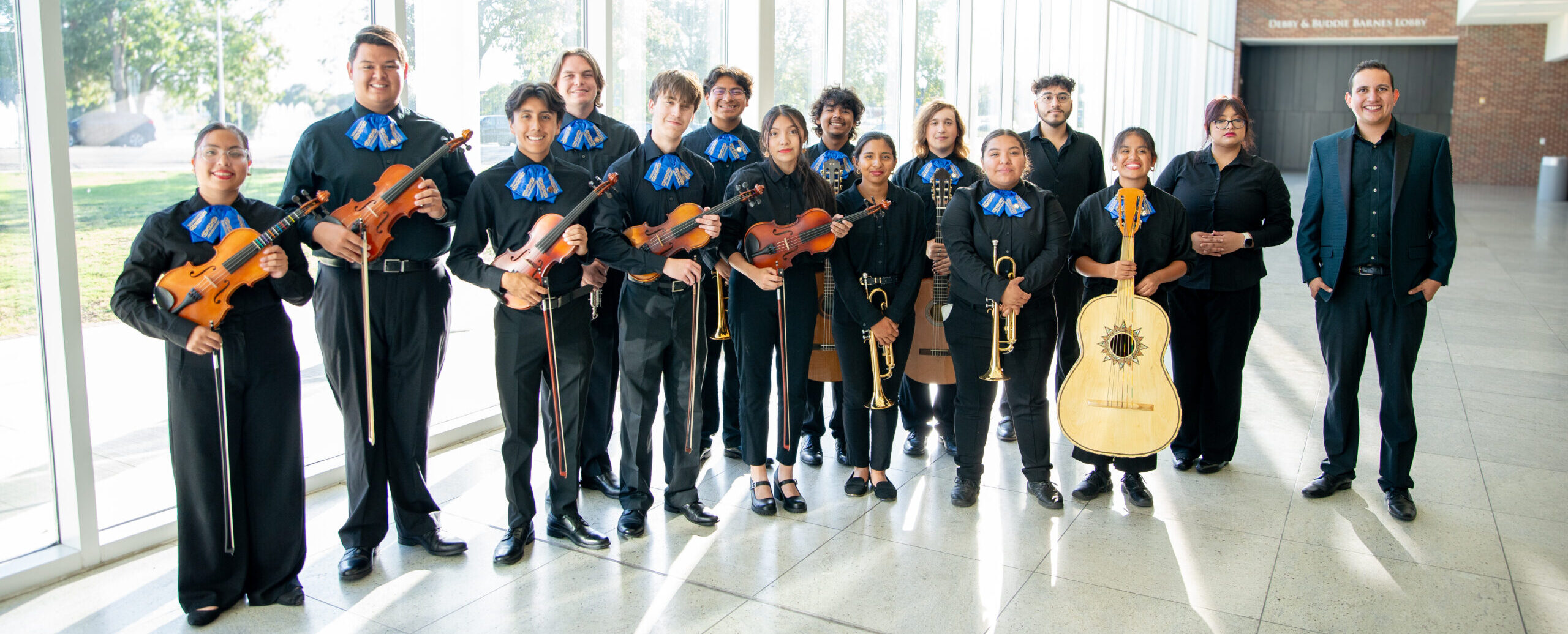 A mariachi ensemble poses for a photo in a marble-floored building lobby.