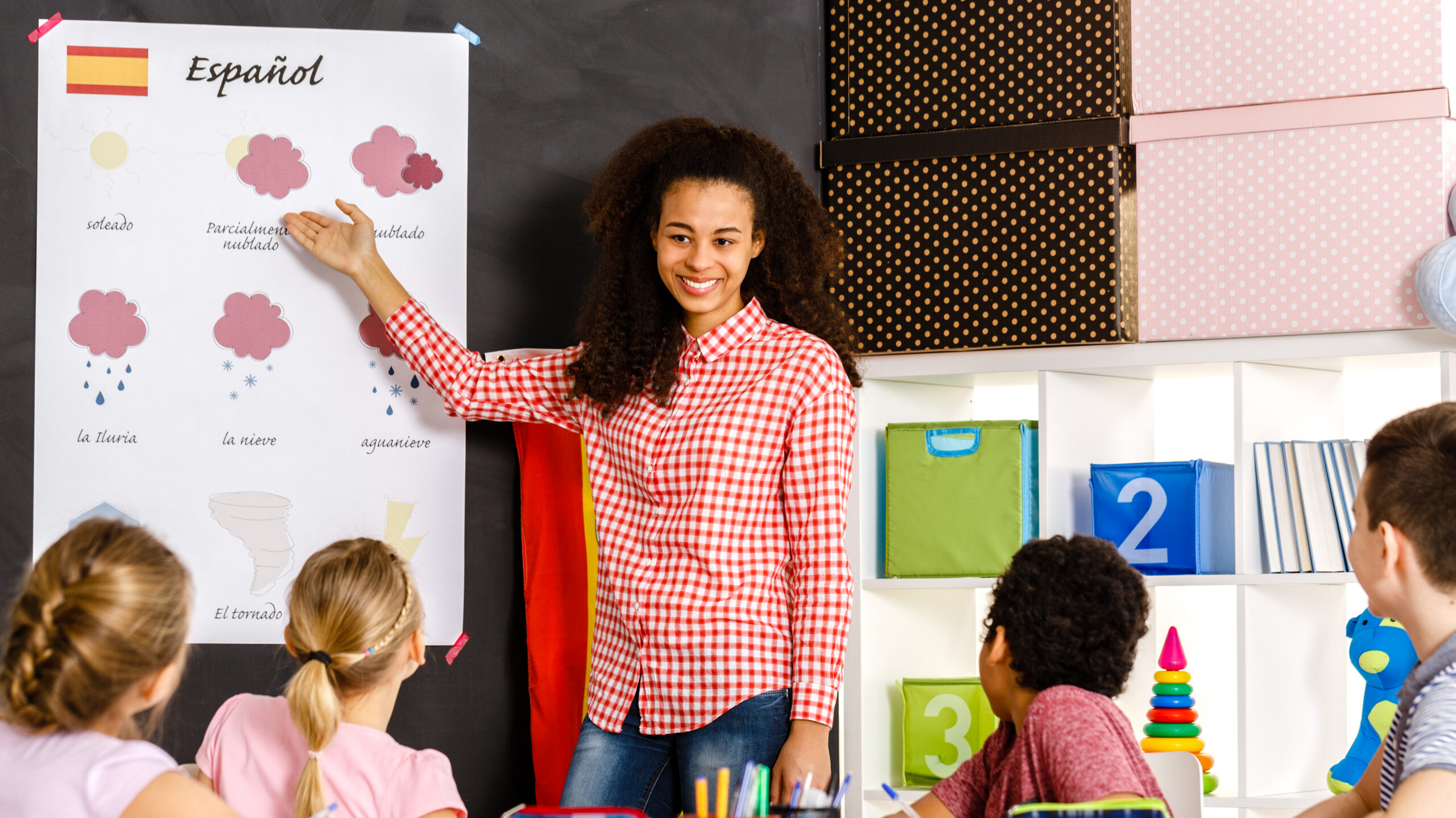 An instructor uses a chart to teach Spanish to young students in a classroom.