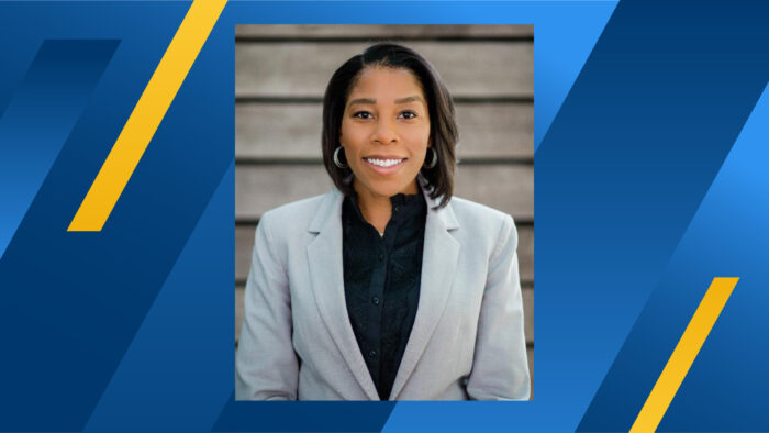 An image of TAMUC alum Dr. Terri D. Osborne wearing a gray business suit displayed over a blue and gold background.