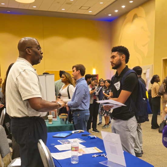 People conversing at a career fair booth.