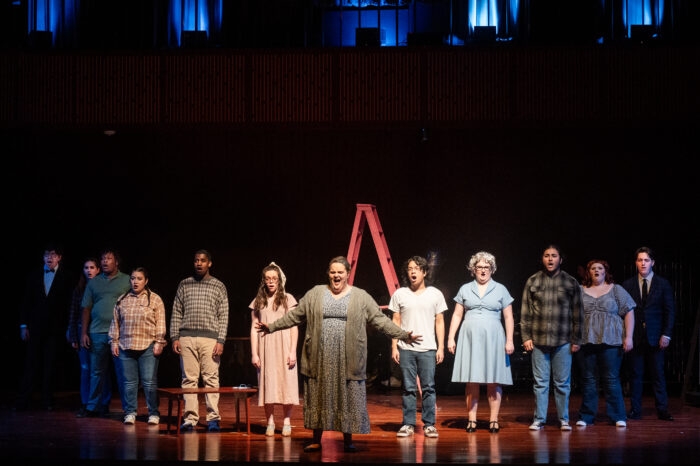 A chorus performing on stage during a musical.