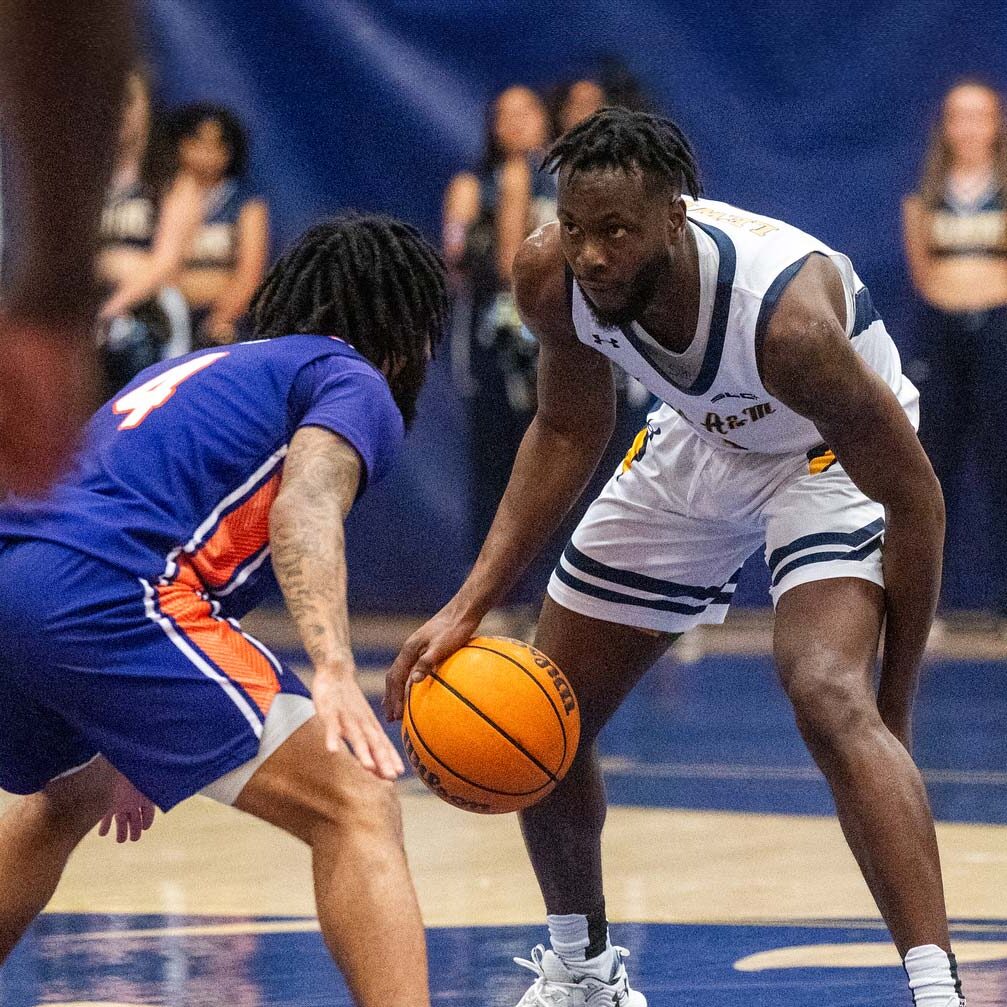 Player in white uniform on the right dribbles the ball. Player in blue uniform on the left defends the ball.