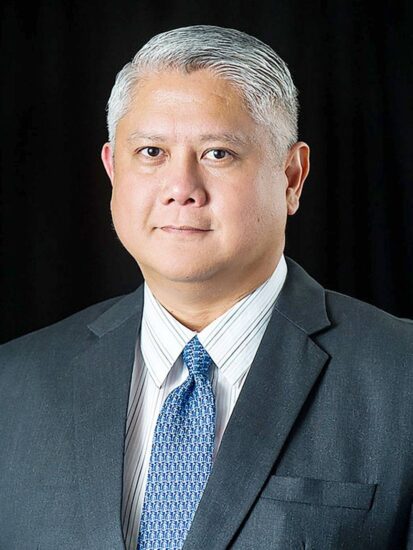 A headshot photo of a person in a suit.