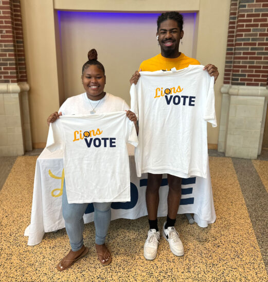 Two students holding up shirts that say Lons Vote