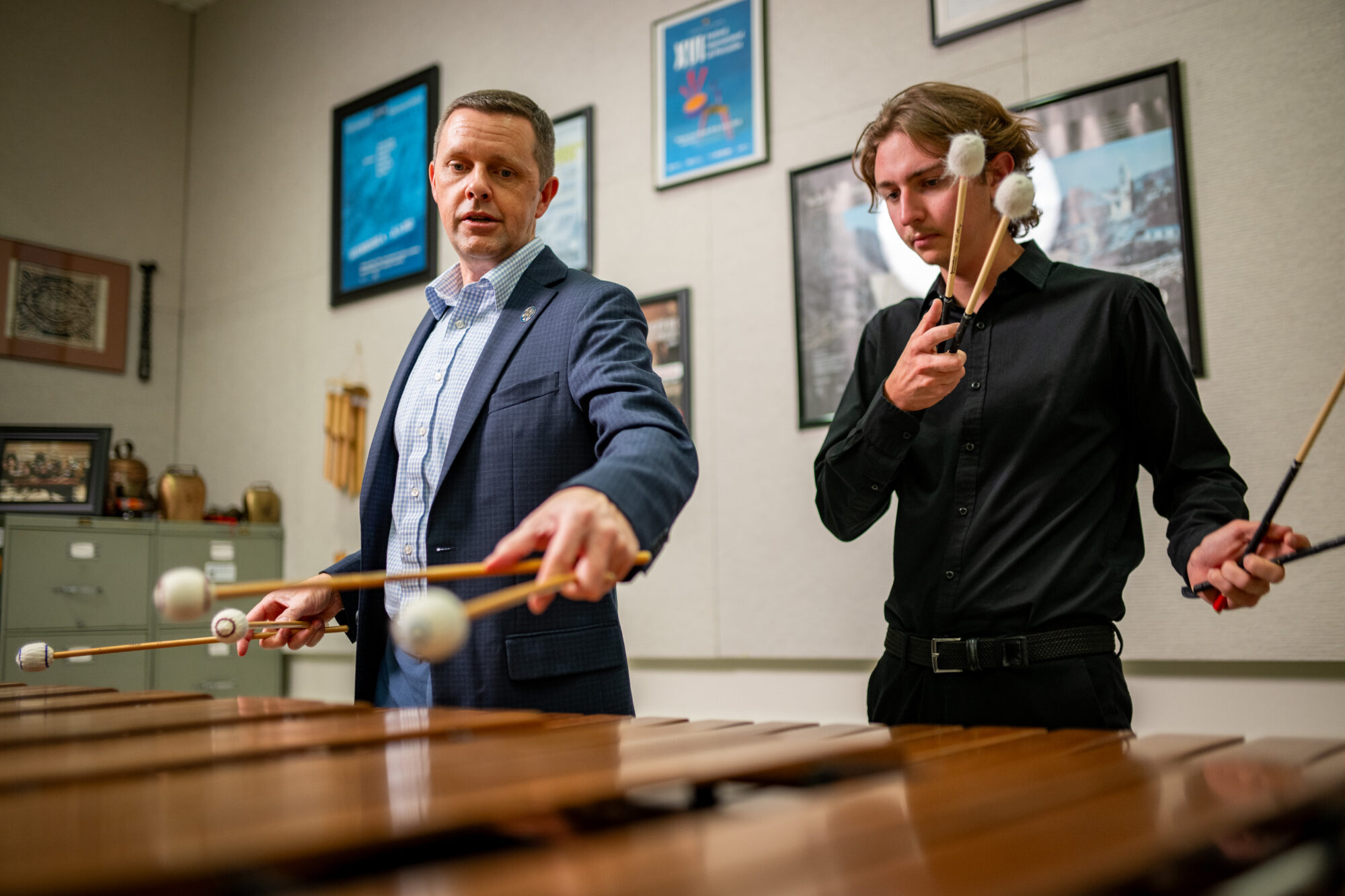 Two people practicing on a marimba instrument.