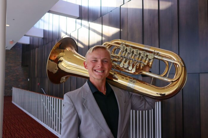 A person posing for a photo while holding a Euphonium.