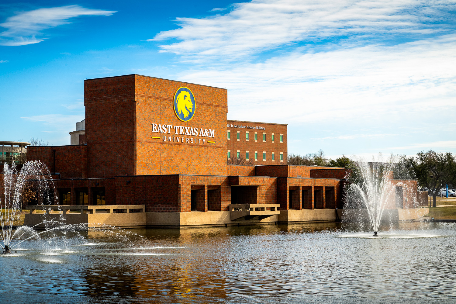 Performing Arts Center of East Texas A&M University with fountains and a clear blue sky.