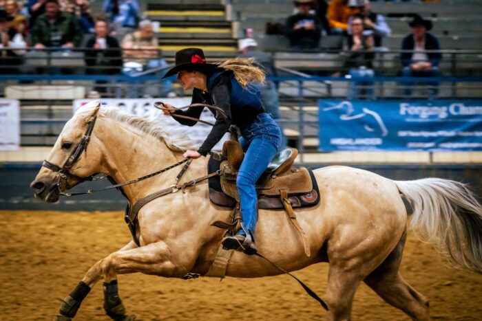 A cowgirl rides a horse during a rodeo competition.