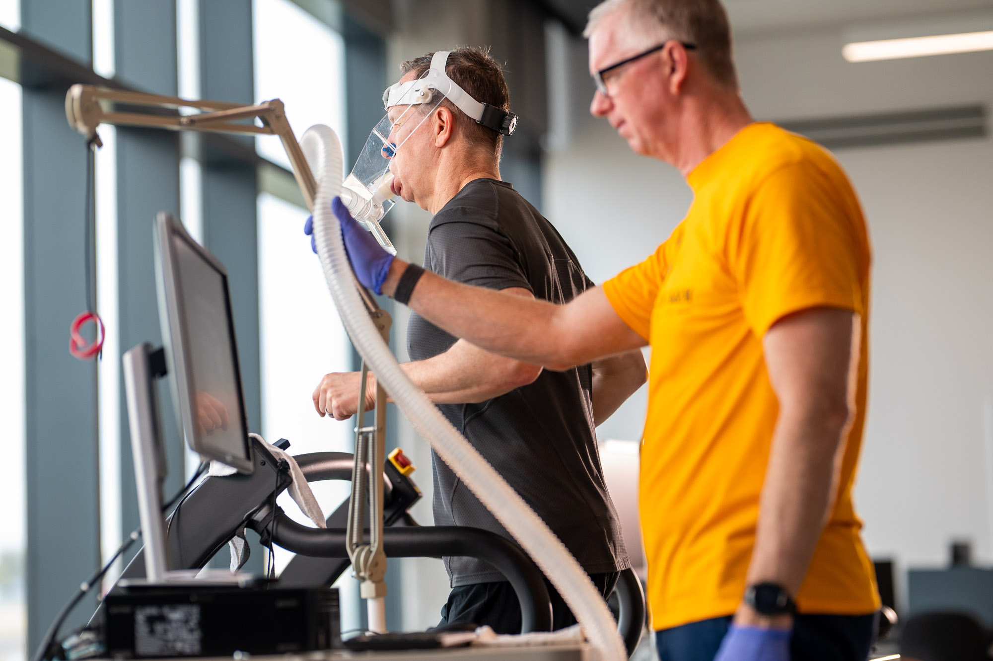 A researcher at East Texas A&M University monitors a participant running on a treadmill while wearing a respiratory mask for a human performance and movement study.