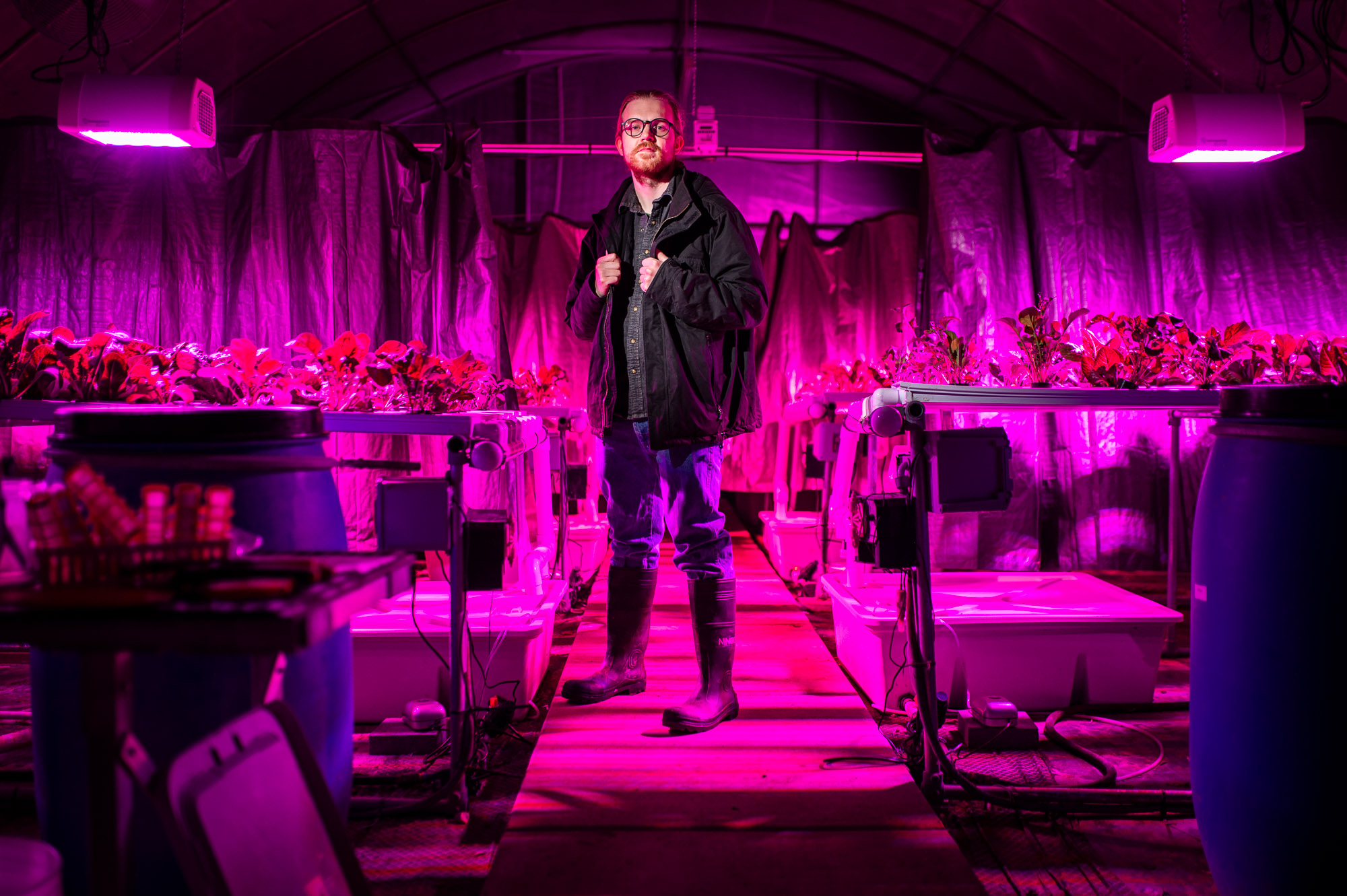 A researcher stands in a high-tech greenhouse at East Texas A&M University, surrounded by hydroponic plants growing under specialized LED lighting.