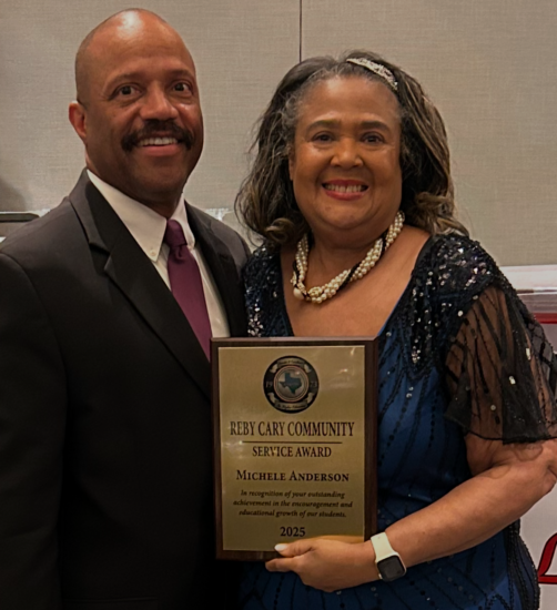 Two people pose for a photo with an award plaque