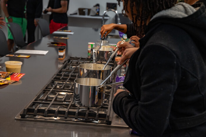 People cooking on a stove with metal pots